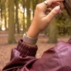 A person's arm wearing a watch and jacket in a forest setting. Produktbild-Vorschau