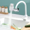 A white faucet with a water filter attachment is shown over a sink with vegetables being rinsed. Produktbild-Vorschau