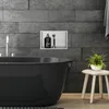 A modern bathroom with a black bathtub, a built-in niche with toiletries, and a small stool with a plant. Náhled obrázku produktu