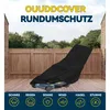 A lawnmower covered by a black protective cover, standing on a wooden deck in front of a wooden fence and trees. Produktbild-Vorschau