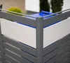 A close-up view of a modern metal trash can enclosure with white panels and gray slats, with a blue trash bin visible inside. Náhled obrázku produktu