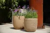 Two planters with flowers are placed on a patio next to a rusty metal structure. Náhľad obrázku produktu