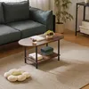 A living room scene with a dark green sofa, a wooden coffee table with two shelves, and a flower-shaped cushion on the floor. Náhled obrázku produktu