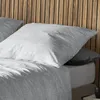 A close-up view of a bed with pillows and a wooden headboard. Produktbild-Vorschau