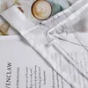 Close-up of a transparent curtain with embroidered details, placed over a book and next to a cup of coffee. Produktbild-Vorschau