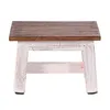 A small wooden stool with a brown top and white legs, isolated on a white background. Produktbild-Vorschau
