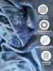 A close-up of a blue plush blanket with marketing icons and text on the right side. Produktbild-Vorschau