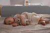 A baby sleeping on a bed with a teddy bear. Voir les images du produit