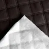 A close-up view of quilted brown material with a white fluffy lining underneath. Náhled obrázku produktu