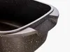 A close-up view of the handle and rim of a dark-colored roasting pan with a speckled pattern. Podgląd zdjęcia produktu