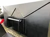 A close-up view of a black metal attachment for a front loader, possibly a bucket or scoop, with visible welding and mounting hardware. Produktbild-Vorschau