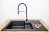 A black granite composite kitchen sink with a pull-down faucet and three heart-shaped cookies on the countertop. Produktbild-Vorschau