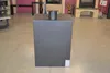 A dark gray wood-burning stove with a metal chimney pipe on top, placed on a light gray floor in what appears to be a showroom or store. Other stoves and furniture are visible in the background. Produktbild-Vorschau