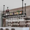 A black metal wine rack with bottles and glasses hanging from it, displayed in what appears to be a bar or dining area. Podgląd zdjęcia produktu