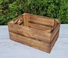 A wooden crate is placed on a light gray surface in front of a green hedge. Produktbild-Vorschau