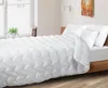 A neatly made bed with a white comforter and pillows. Náhled obrázku produktu