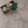 A wooden tray with a candle, a small vase with dried flowers, and a green book rests on a geometric patterned rug. Produktbild-Vorschau