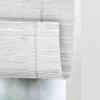 A close-up view of a white bamboo roller blind hanging in front of a window. Náhled obrázku produktu
