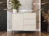 A modern, minimalist kommode with a fluted door and three drawers, placed in a well-lit room with decorative elements. Náhľad obrázku produktu