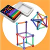 A set of magnetic building sticks and balls, along with a storage tin, are displayed against a white and orange background. Several structures built from the magnetic pieces are also shown. Náhled obrázku produktu