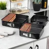 Three square springform pans are arranged on a countertop, with two of them containing slices of chocolate cake. A white oven mitt is placed to the left of the pans. Anteprima dell’immagine prodotto