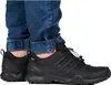 A person wearing black Adidas Terrex hiking shoes and blue jeans. Anteprima dell’immagine prodotto