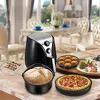 A collection of air fryer accessories and food items are displayed on a marble countertop in a dining room setting. Voir les images du produit