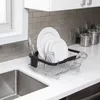 A dish rack with plates, glasses, and cutlery placed on a white kitchen countertop next to a sink. Produktbild-Vorschau