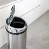 A close-up shot of an automatic kitchen trash can with its lid open, placed on a light gray floor in front of white kitchen cabinets. Anteprima dell’immagine prodotto
