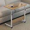 A portable, height-adjustable wooden work table with wheels is placed next to a sofa. Produktbild-Vorschau