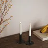 Two white LED candles in black holders are placed on a wooden surface next to a book and decorative branches. Produktbild-Vorschau
