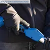 A person wearing gloves is holding a blue and black tool, possibly a hedge trimmer, with a safety switch visible. Náhľad obrázku produktu