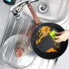 A frying pan with food residue is being washed in a sink with a sponge. Produktbild-Vorschau
