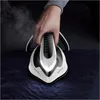 A hand holding a steam iron over a dark fabric. Produktbild-Vorschau