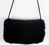 A black faux fur hand muff with a thin black cord strap is shown hanging against a white background. Produktbild-Vorschau