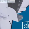 A close-up view of a white metal component with screws, part of a larger machine, set against a blue background. Produktbild-Vorschau