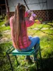 A person is gardening and pruning a tree while sitting on a garden stool. Produktbild-Vorschau
