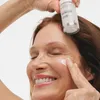 A woman applies serum to her face. Produktbild-Vorschau