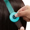 A close-up shot of a person's hand holding a teal hair accessory tool to add teal hair extensions to dark brown hair. Náhľad obrázku produktu