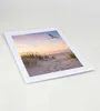A framed picture of a beach scene with a seagull flying at sunset. Produktbild-Vorschau
