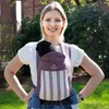 A woman is wearing a baby carrier with a baby inside, outdoors. Produktbild-Vorschau