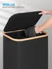 A person is putting laundry into a black laundry basket with a wooden rim and lid. Náhled obrázku produktu