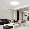 A modern living room with a sectional sofa, coffee table, and ottoman, illuminated by a ceiling light. Produktbild-Vorschau