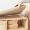 A hand is shown placing a beige cushion on top of a wooden storage unit. Produktbild-Vorschau