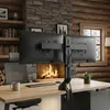 A dual monitor desk mount is shown on a wooden desk in front of a fireplace. Podgląd zdjęcia produktu