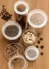 Several glass storage containers filled with various dry goods, arranged on a wooden surface. Produktbild-Vorschau