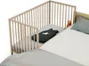 A baby crib attached to a larger bed, with a sleeping bag and a teddy bear inside. Anteprima dell’immagine prodotto