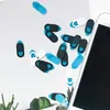 Sortiment aus blauen, schwarzen und weißen Webcam-Sichtschutzabdeckungen, verstreut auf weißer Oberfläche neben einem Smartphone und kleinen Pflanzen Produktbild-Vorschau
