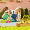 A woman and a child are gardening together in a sunny backyard, planting flowers in raised garden beds. Produktbild-Vorschau