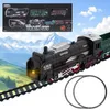 A toy train set is displayed on a track with a mountainous landscape and sky in the background. A box showing different train set components is in the upper left corner. Produktbild-Vorschau